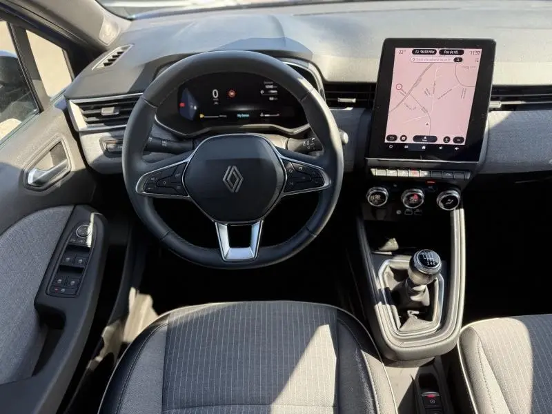 Vue intérieure frontale du poste de conduite de la Renault Clio 1.0 TCe 90ch Techno 2025 avec écran tactile vertical et levier de vitesse manuel.