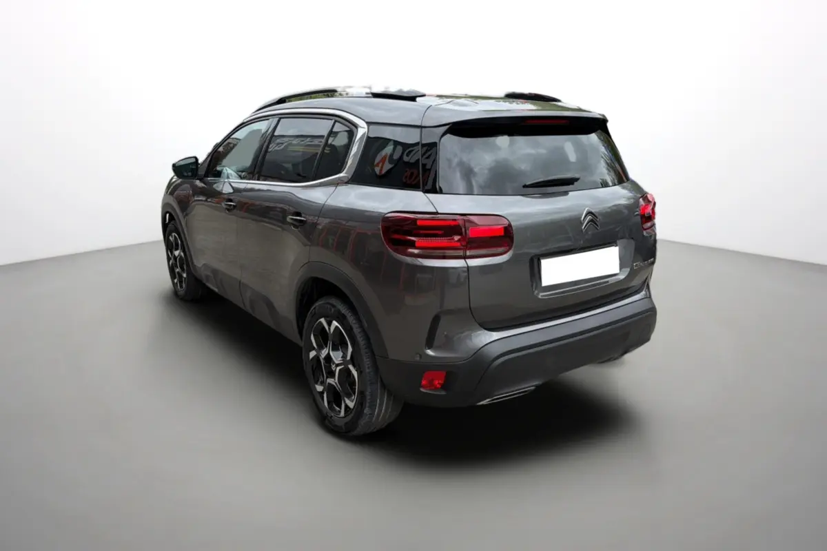 Vue 3/4 arrière droite d'un Citroën C5 Aircross gris platinium avec vitres surteintées et jantes alu 18 pouces.