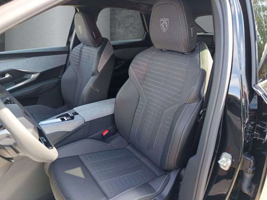 Intérieur du Peugeot 3008 2025 noir perla nera, vue côté gauche sur sièges avant avec logo GT brodé sur appuie-tête.