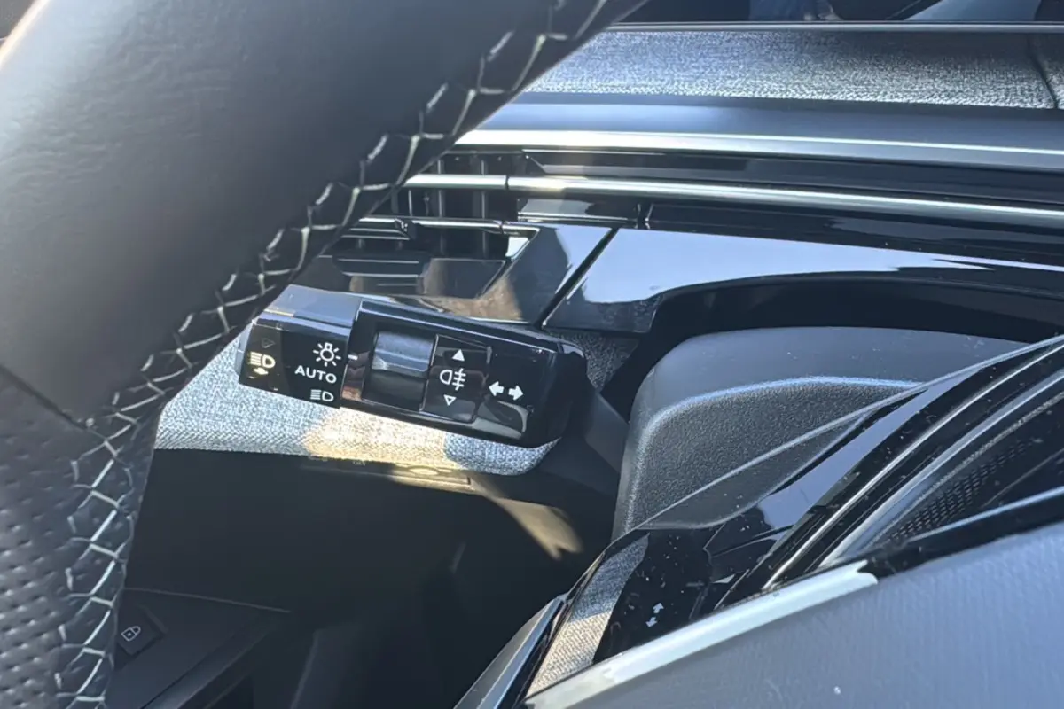 Gros plan sur la commande des feux et clignotants côté gauche du tableau de bord du Peugeot 3008 noir perla nera 2025.