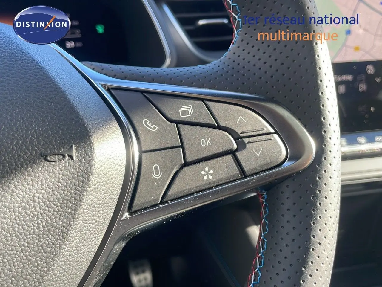 Gros plan sur les commandes au volant perforé avec surpiqûres tricolores du Renault Captur gris rafale toit noir.