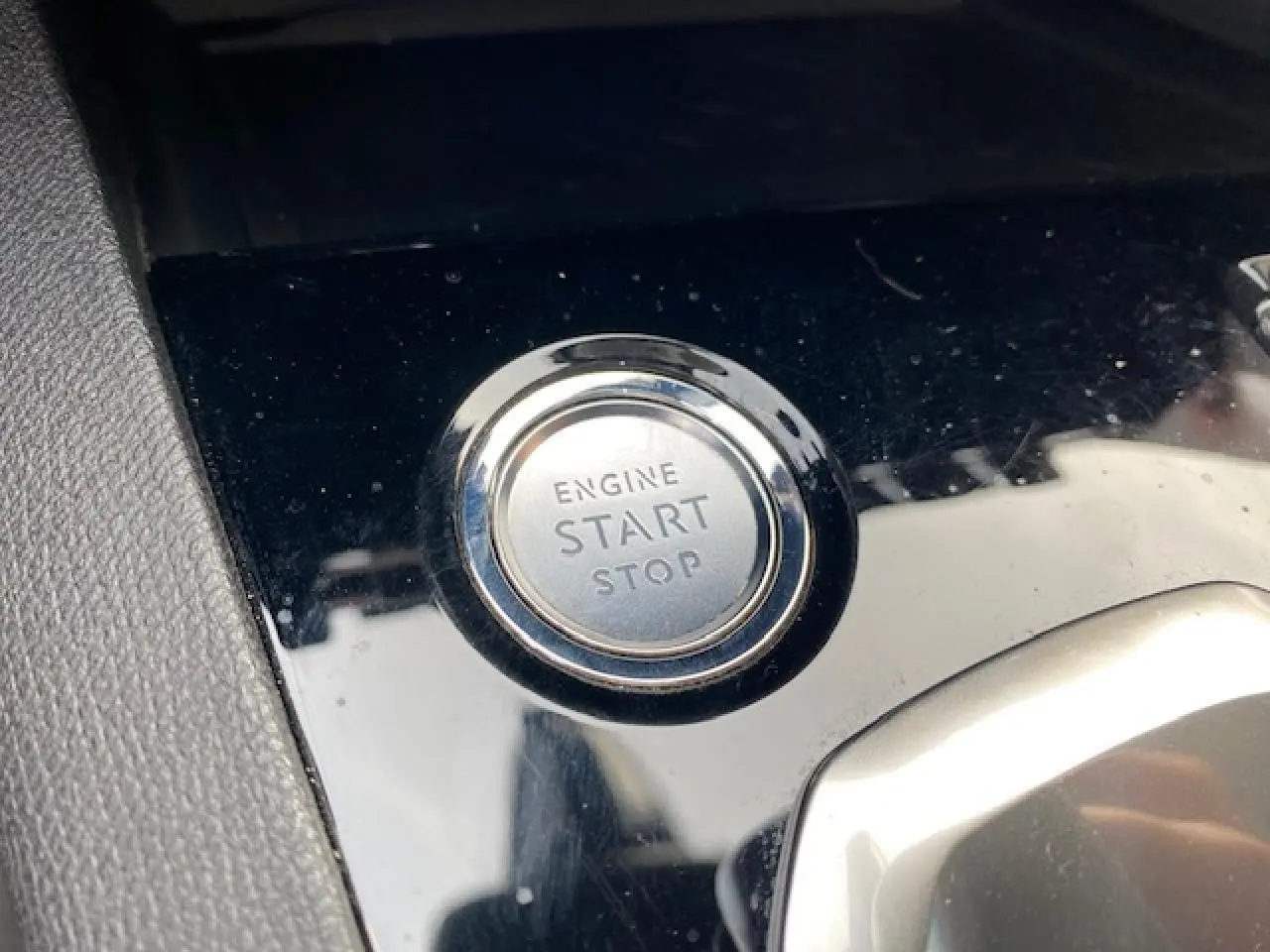 Bouton start/stop moteur en gros plan sur la console noire brillante du Peugeot 3008 gris platinium de 2021.