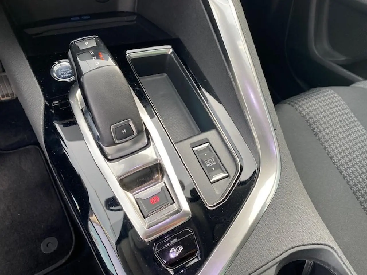Gros plan sur la console centrale noire brillante du Peugeot 3008 2021, avec levier de vitesse automatique et bouton Drive Mode.