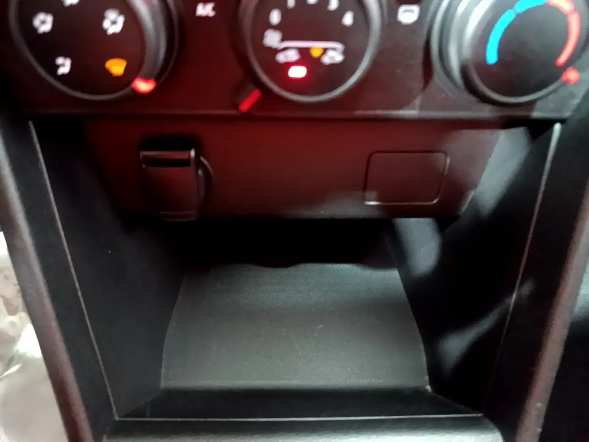 Gros plan sur la console centrale noire de la Dacia Sandero Confort TCe 90 2022, avec commandes de climatisation visibles.