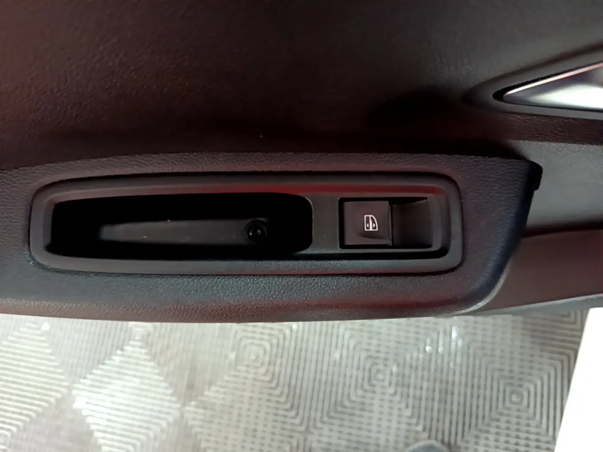 Gros plan sur la commande de lève-vitre côté conducteur de la Dacia Sandero Confort blanche, intérieur noir.