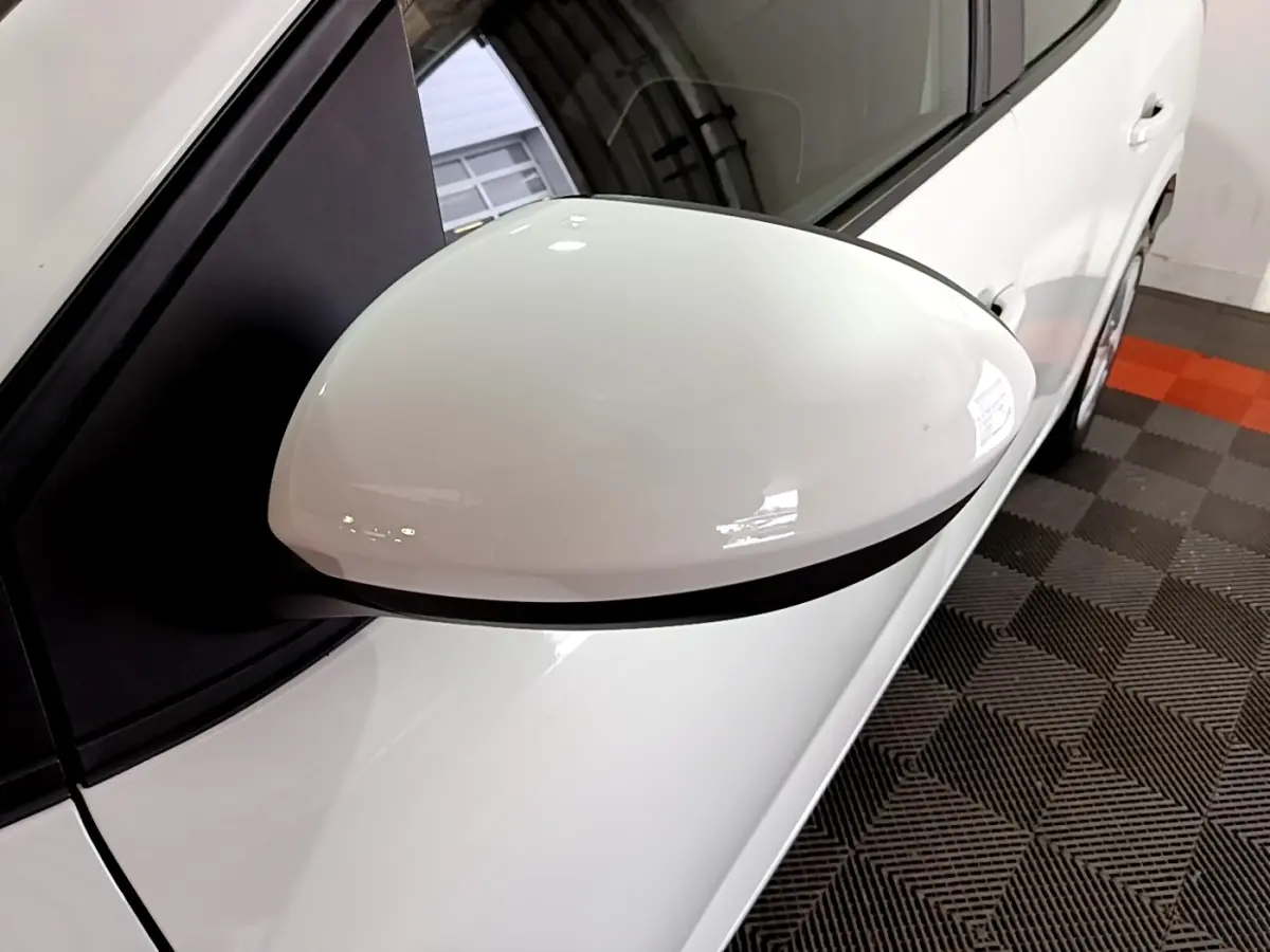 Gros plan sur le rétroviseur côté gauche blanc de la Dacia Sandero Confort TCe 90 -22B, vue partielle du véhicule.