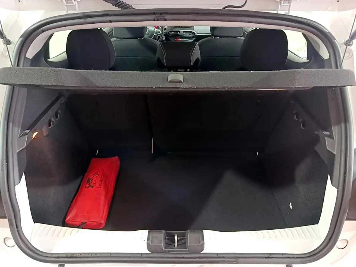Coffre ouvert vu de l'arrière d'une Dacia Sandero blanc 2022, avec trousse de secours rouge à gauche.