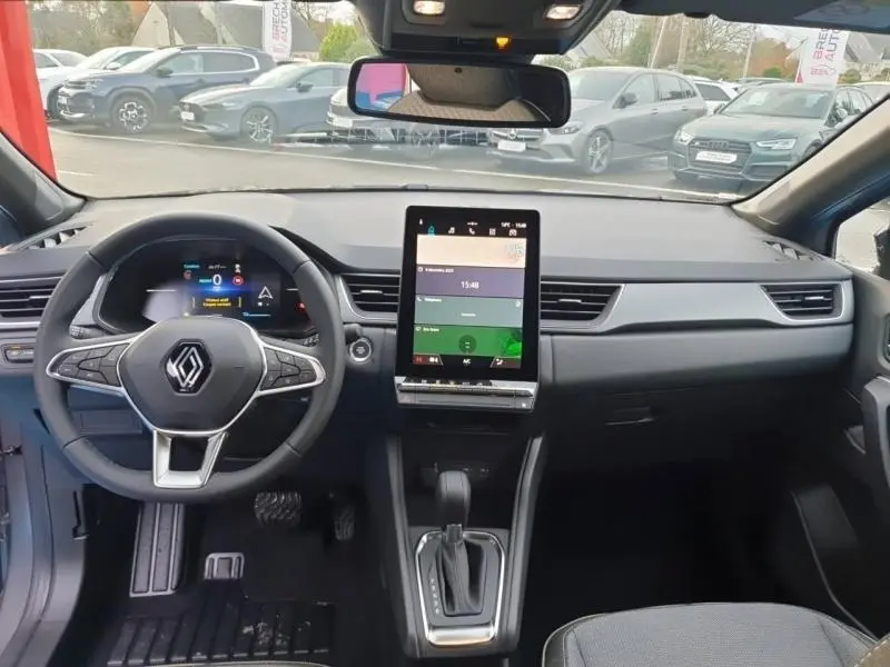 Vue intérieure avant du Renault Captur 2025 gris Cassiopée, avec tableau de bord moderne et écran tactile vertical central.