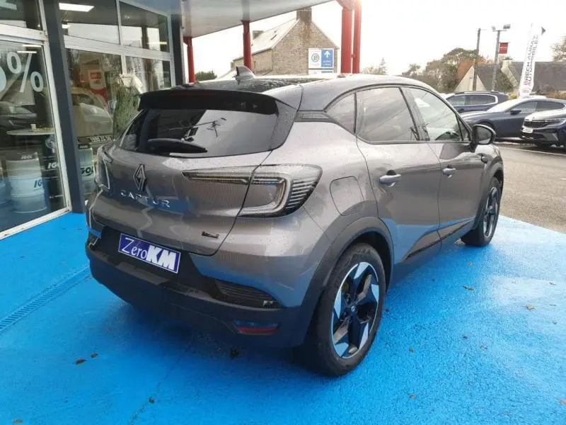 Vue 3/4 arrière droite d'un Renault Captur gris Cassiopée avec vitres teintées et jantes alliage bicolores.