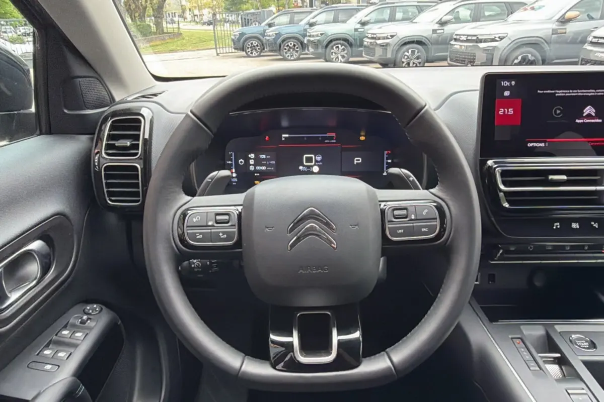 Vue intérieure centrée sur le volant cuir multifonctions du Citroën C5 Aircross Hybrid 2025 avec tableau de bord numérique et écran tactile.