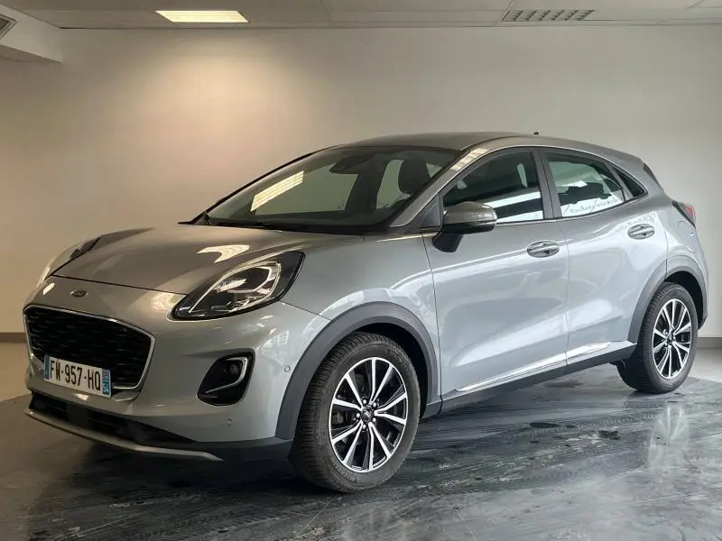 Ford Puma gris Solar métallisé en vue 3/4 avant droit, jantes alu et phares LED dans un intérieur neutre.