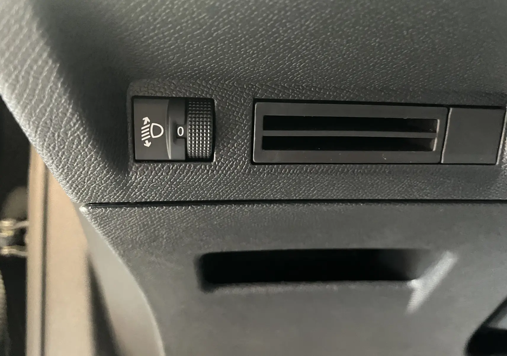 Gros plan sur le réglage d'inclinaison des phares et la sortie d'aération côté conducteur du Peugeot 3008 noir 2025.