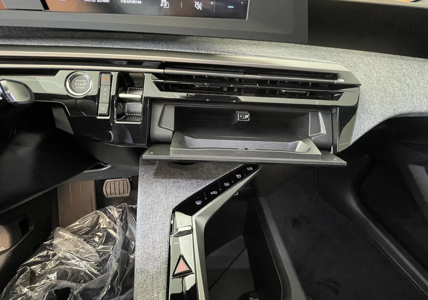 Intérieur du Peugeot 3008 Allure 2025, vue sur la console centrale avec boîte auto, bouton start et boîte à gants ouverte.