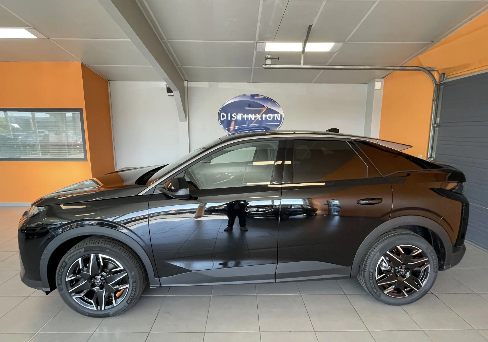 Profil côté gauche du Peugeot 3008 noir 2025 avec jantes alliage 19 pouces en intérieur showroom.