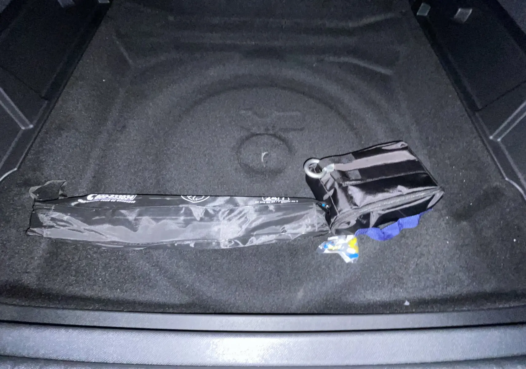 Coffre noir du Peugeot 3008 NV HYBRID 136 E-DCS6 Allure avec kit de dépannage pneumatique rangé.