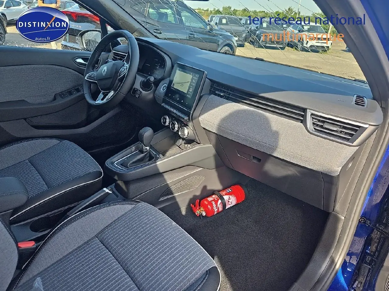 Vue intérieure côté passager d'une Renault Clio V bleu iron, avec tableau de bord moderne et sièges gris tissu.