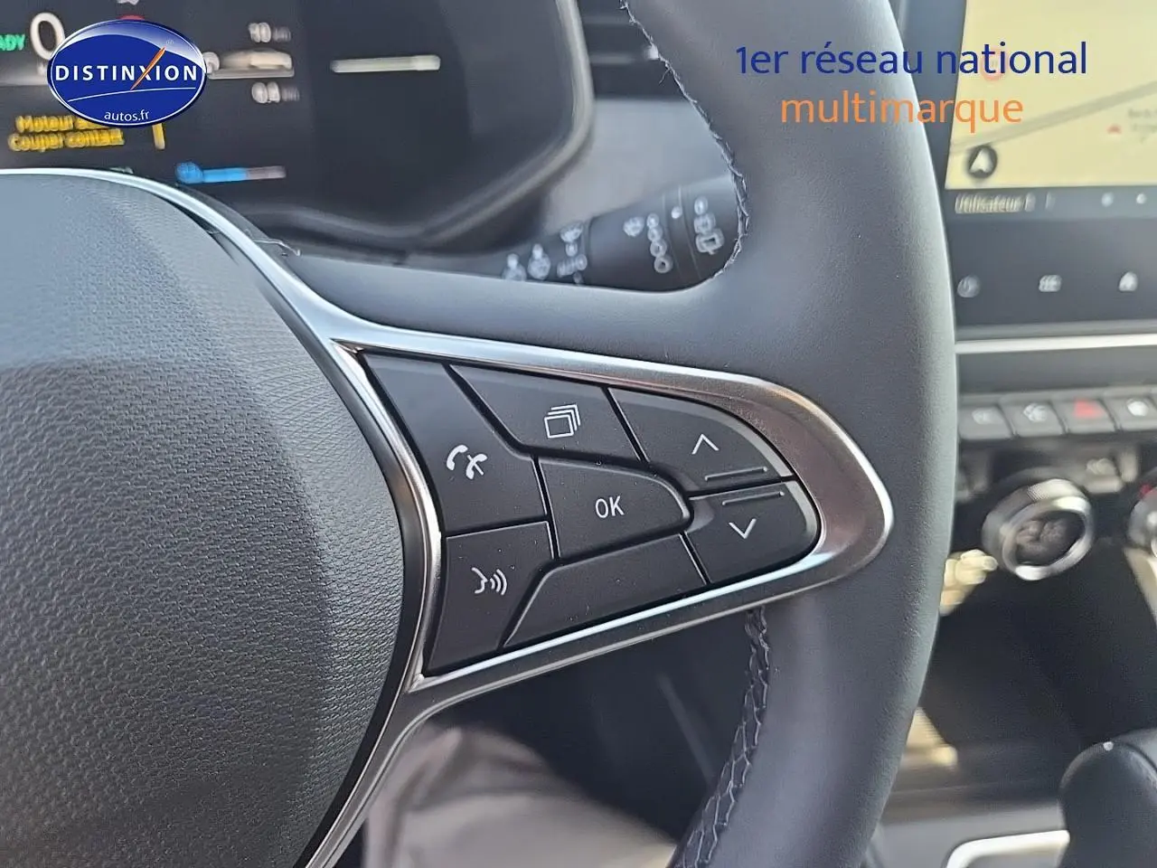 Gros plan sur les commandes multifonctions côté droit du volant de la Renault Clio V bleu iron, avec écran tactile en arrière-plan.