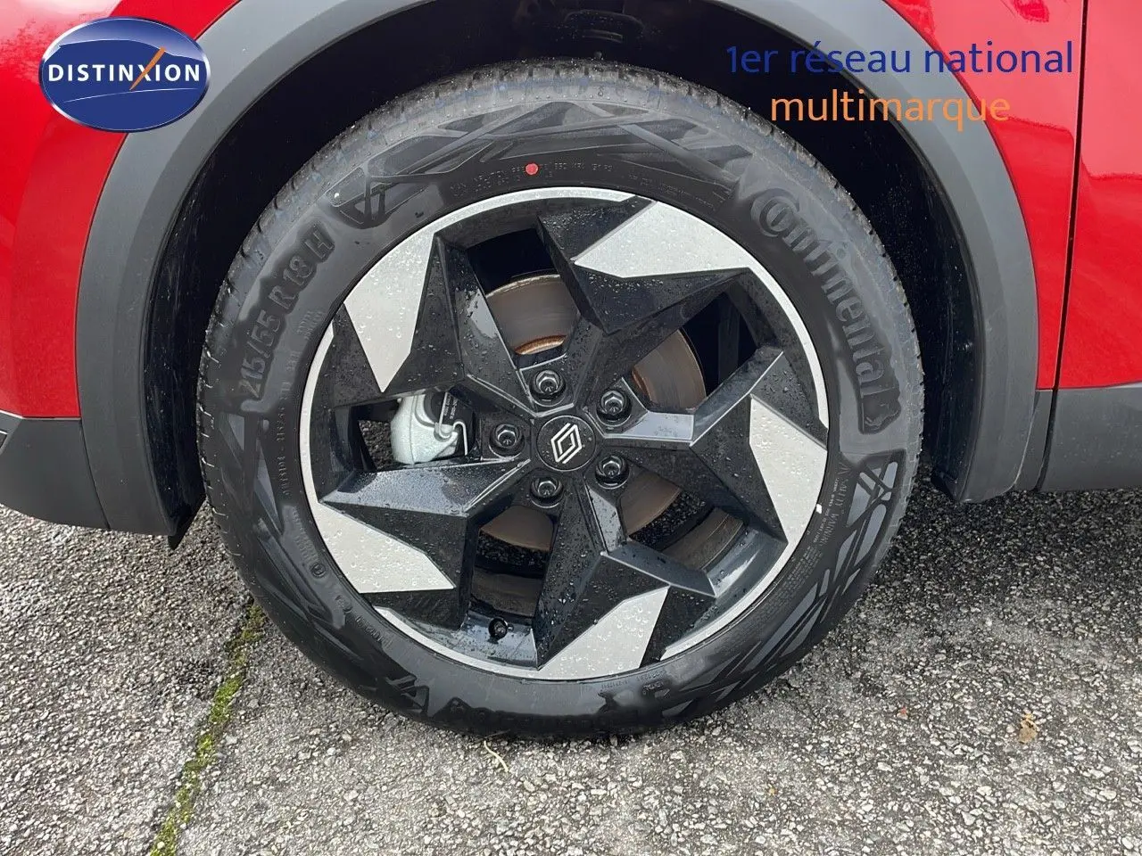 Gros plan sur la roue avant droite du Renault Captur rouge passion avec jante noire et argentée au design géométrique.