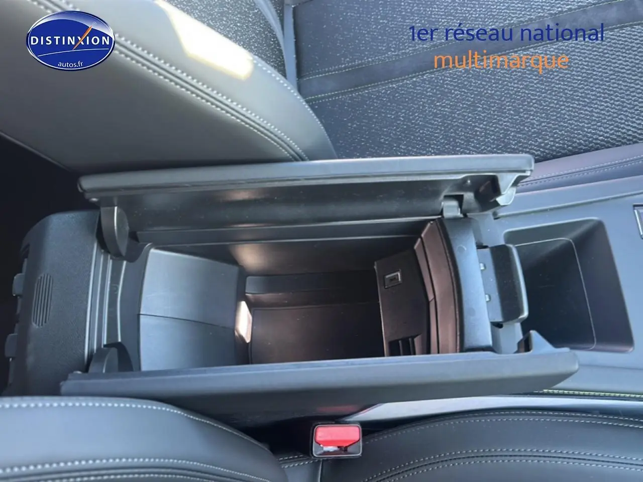 Vue plongeante sur l'accoudoir central noir ouvert du Peugeot 408 Hybrid 145 GT, montrant le rangement intérieur.
