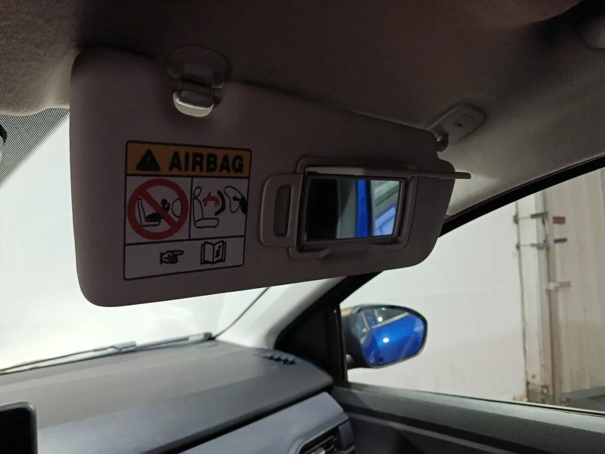 Détail intérieur du pare-soleil côté conducteur avec miroir, reflet bleu de la Dacia Sandero Extreme+ visible dans le rétroviseur.