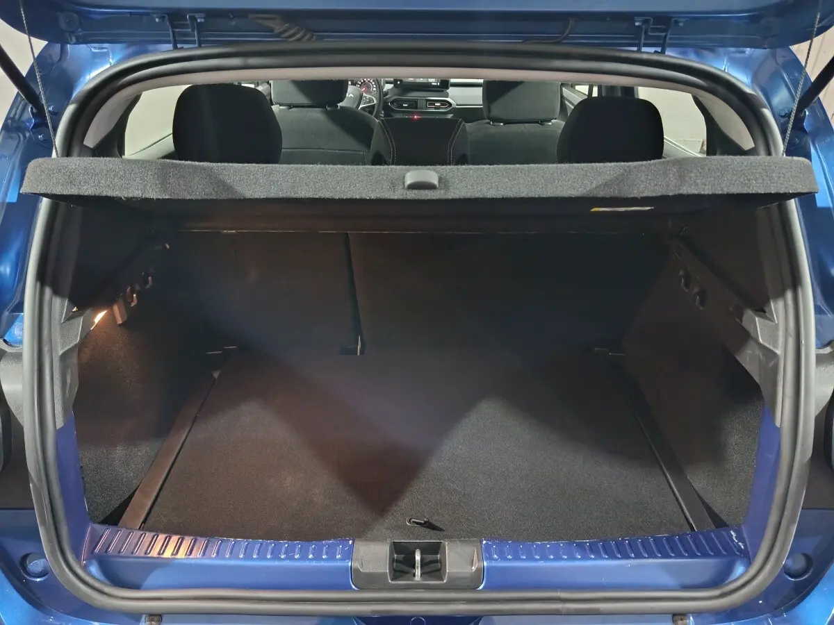 Coffre ouvert vu de l'arrière d'une Dacia Sandero Extreme+ TCe 110 bleu 2024, avec tablette cache-bagages.