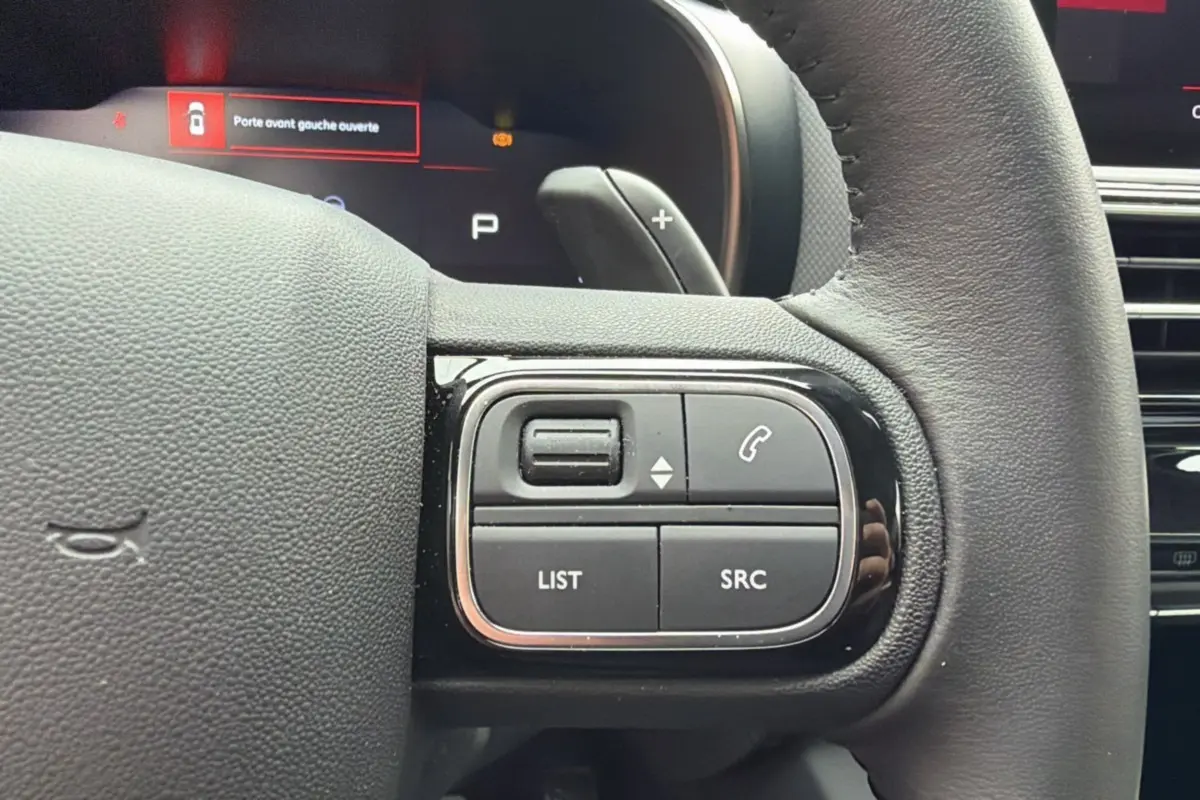 Gros plan sur les commandes multifonctions à droite du volant cuir du Citroën C5 Aircross Hybrid 2025.