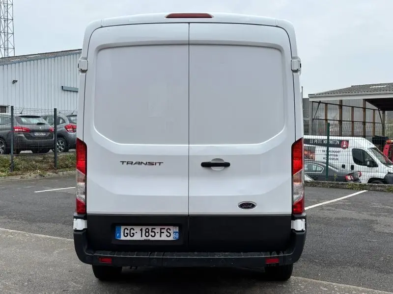 Vue arrière d'un fourgon Ford Transit blanc Glacier avec portes battantes et plaque d'immatriculation française visible