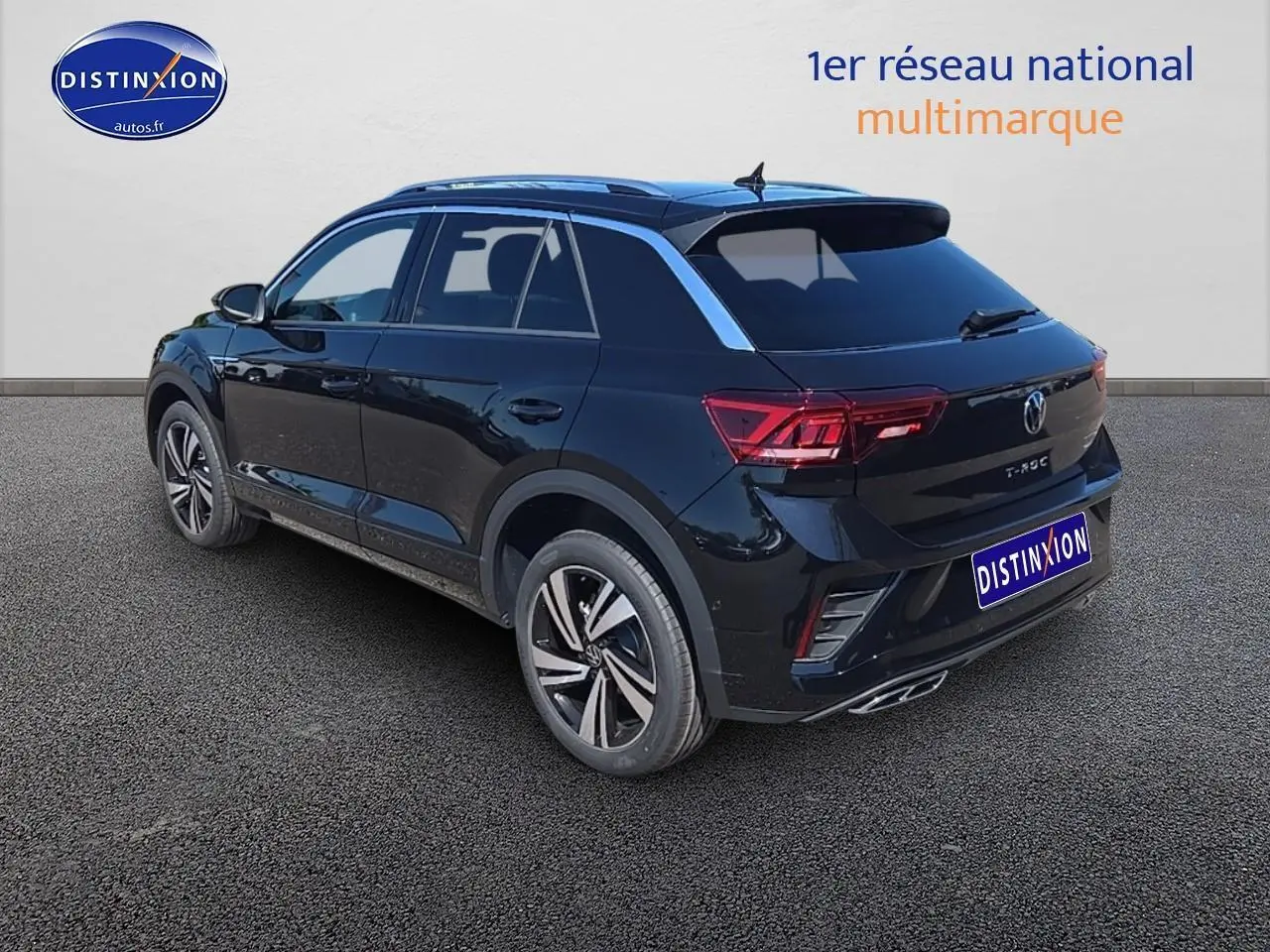 Volkswagen T-Roc noir perle en 3/4 arrière droit avec jantes alliage et barres de toit argentées visibles.