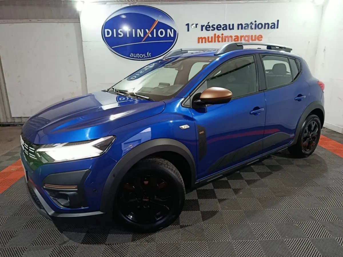 Vue 3/4 avant droite d'une Dacia Sandero Extreme+ TCe 110 2024 bleu avec rétroviseurs bronze et jantes noires.