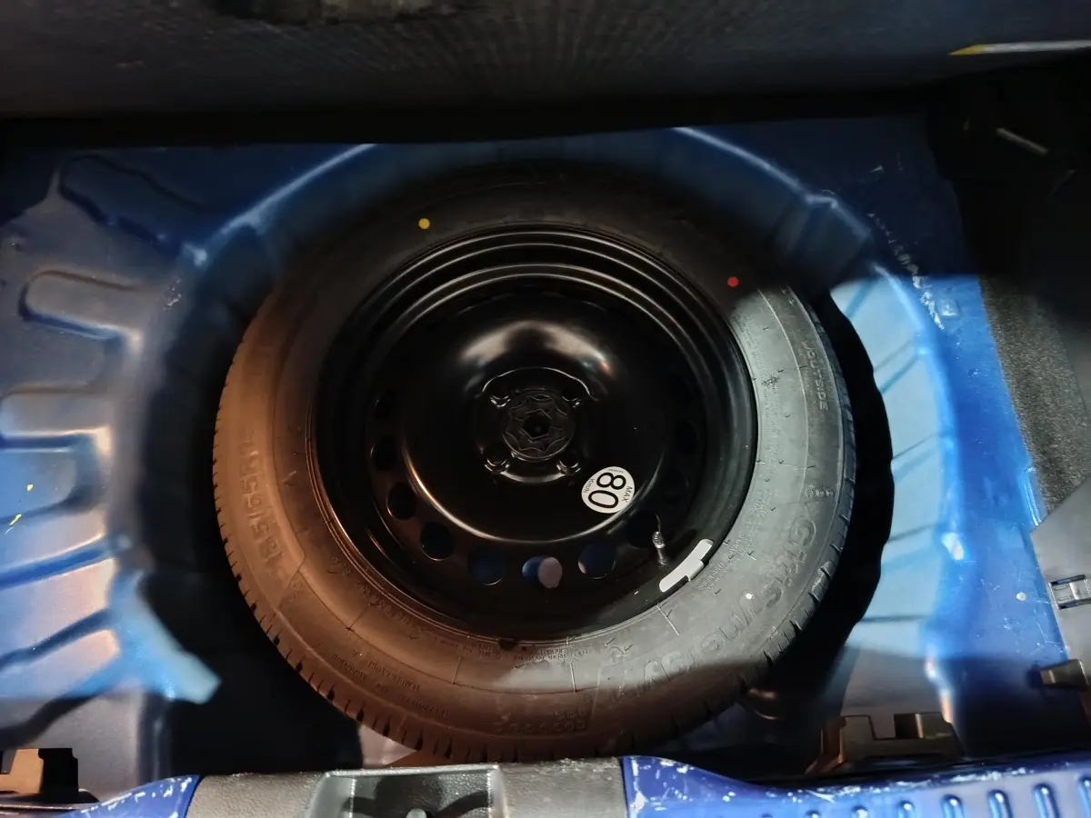 Roue de secours galette en jante acier dans le coffre bleu de la Dacia Sandero Extreme+ TCe 110 2024.