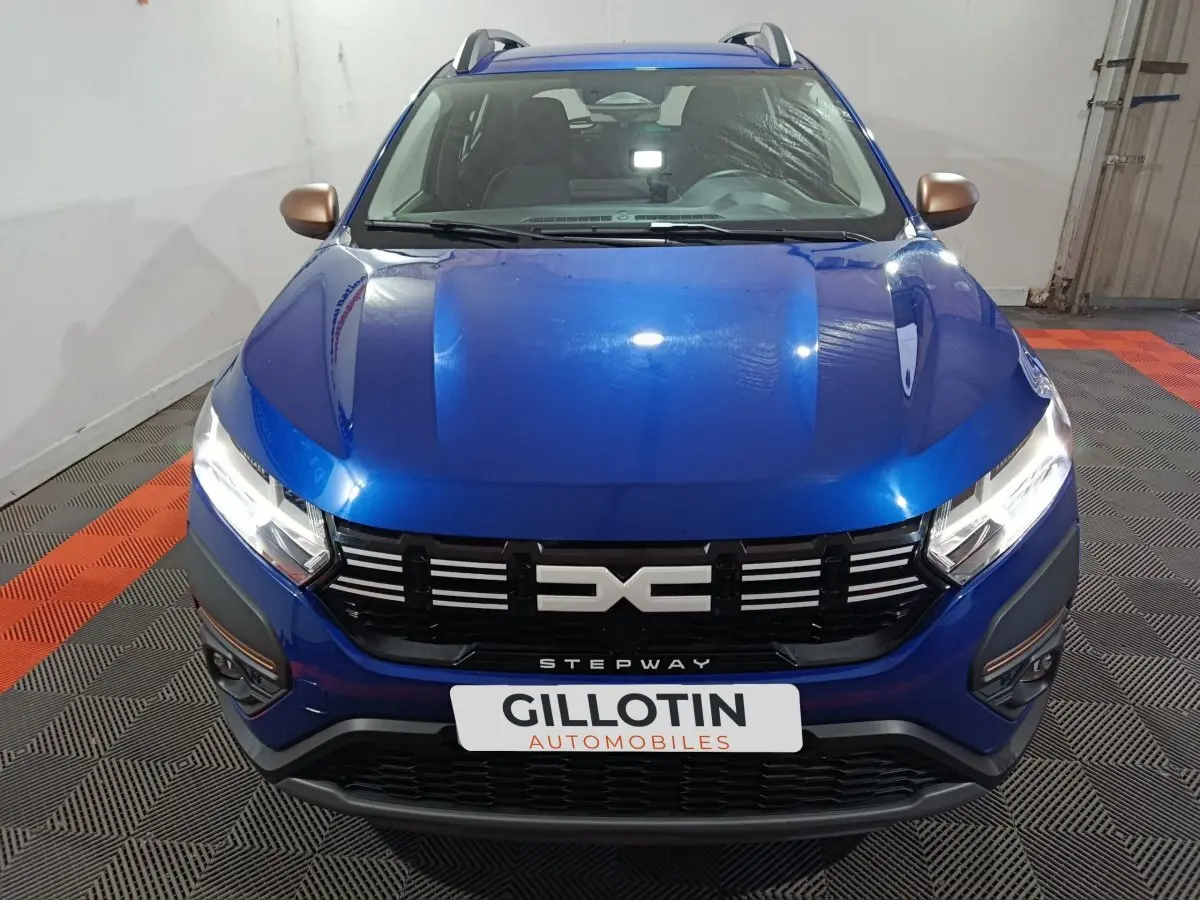 Vue avant d'une Dacia Sandero Extreme+ TCe 110 2024 bleu avec calandre noire et rétroviseurs bronze.