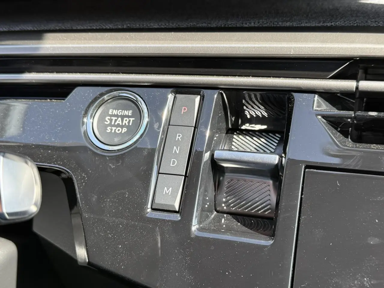 Gros plan sur la console centrale noire brillante du Peugeot 3008 Hybrid 145 Allure avec bouton start/stop et commandes de boîte auto.
