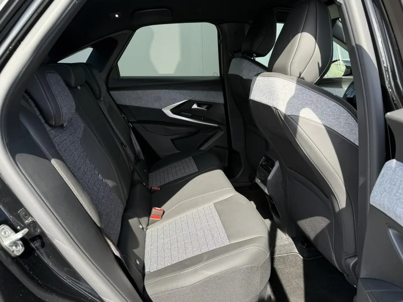 Vue côté gauche de l'habitacle arrière du Peugeot 3008 Hybrid 145 Allure noir Perla avec sellerie tissu et cuir gris clair.