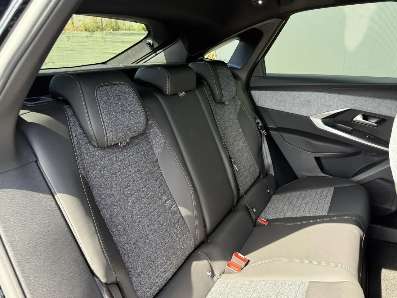 Vue latérale droite des sièges arrière en tissu gris et cuir noir du Peugeot 3008 Hybrid 145 e-DSC6 Allure 2025.