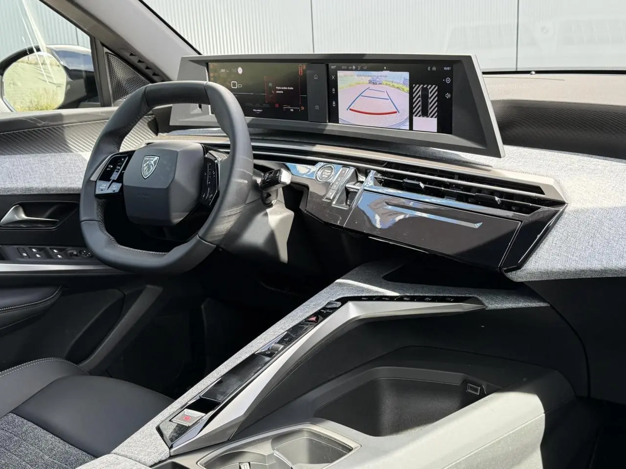 Vue intérieure côté conducteur du Peugeot 3008 Hybrid 2025, volant compact et double écran HD affichant caméra de recul.