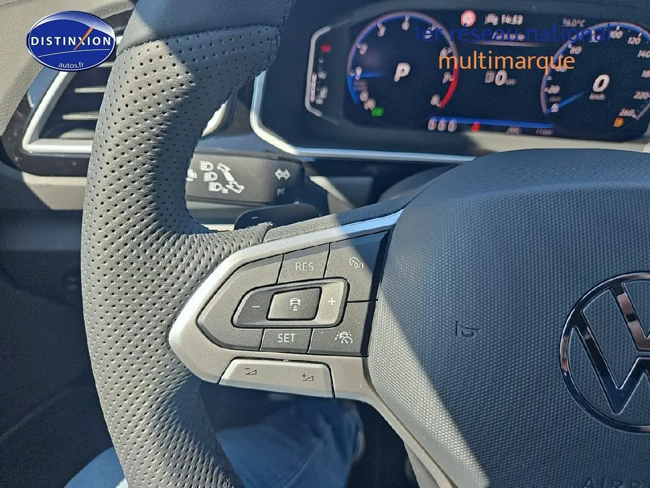 Gros plan sur le volant cuir perforé côté gauche du Volkswagen T-Roc noir perle avec commandes multifonctions et tableau de bord numérique.