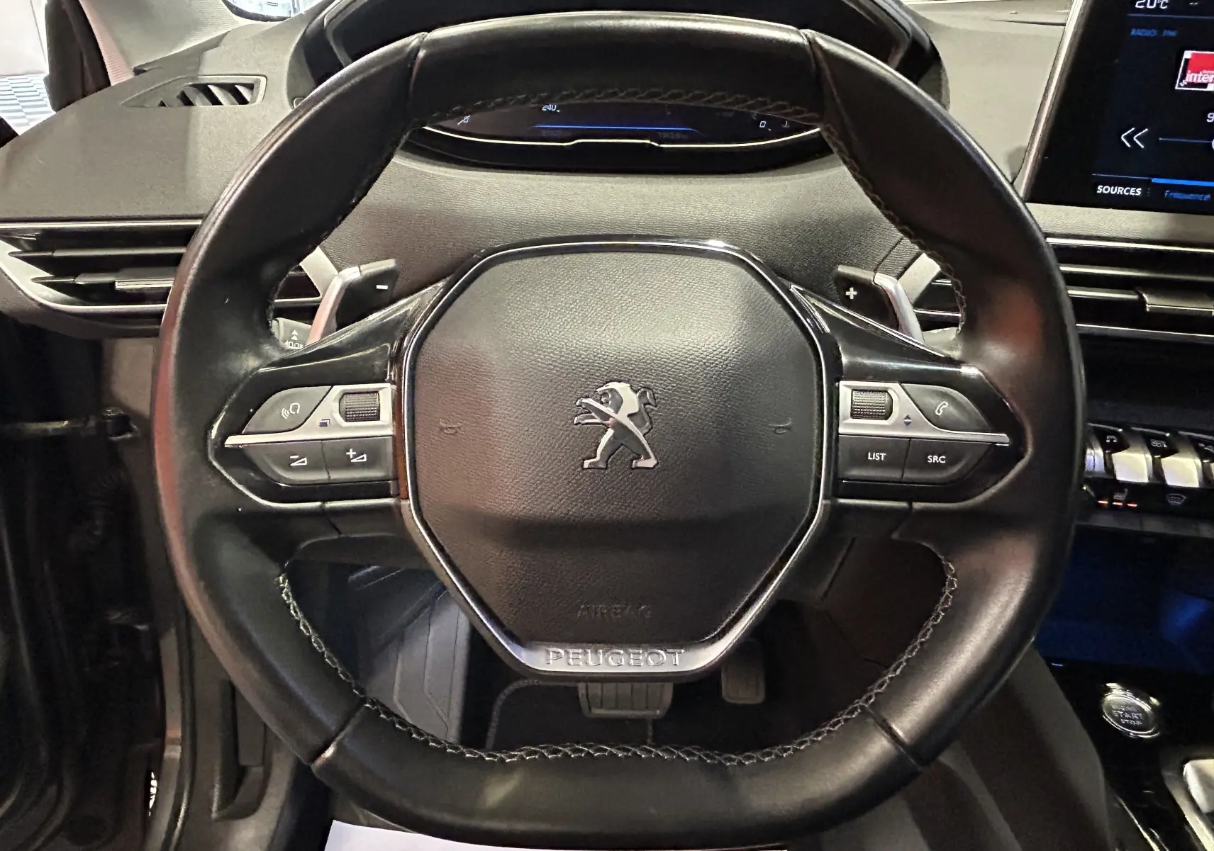 Volant en cuir noir de Peugeot 5008 2020 avec commandes intégrées, tableau de bord et écran tactile visibles en arrière-plan.