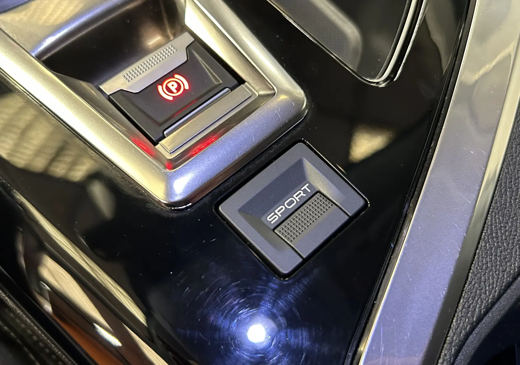 Gros plan sur les commandes de frein à main électrique et mode Sport dans l'habitacle noir du Peugeot 5008 gris 2020.