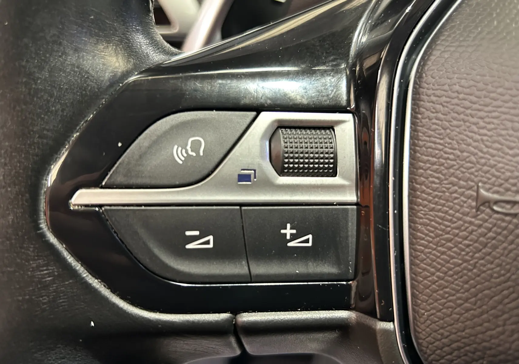 Gros plan sur les commandes de volume et de reconnaissance vocale au volant du Peugeot 5008 gris 2020.