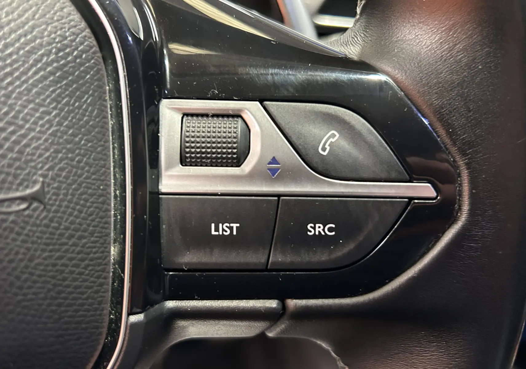 Gros plan sur les commandes noires et argentées du volant du Peugeot 5008 gris, version BlueHDi 130 EAT8 Allure.