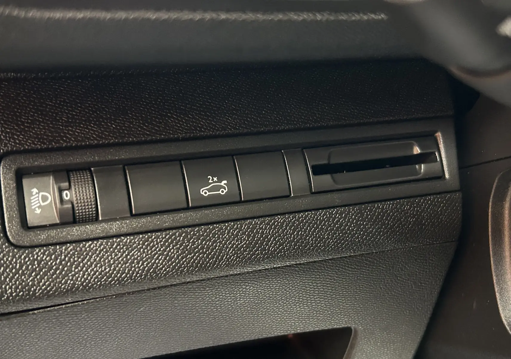 Détail intérieur montrant les commandes noires du tableau de bord du Peugeot 5008 gris, avec bouton hayon et réglage phare.