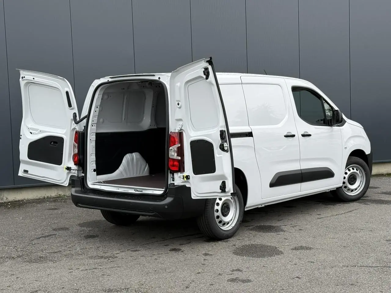 Vue 3/4 arrière droite du Peugeot Partner XL blanc avec portes arrière ouvertes montrant l'espace de chargement vide.