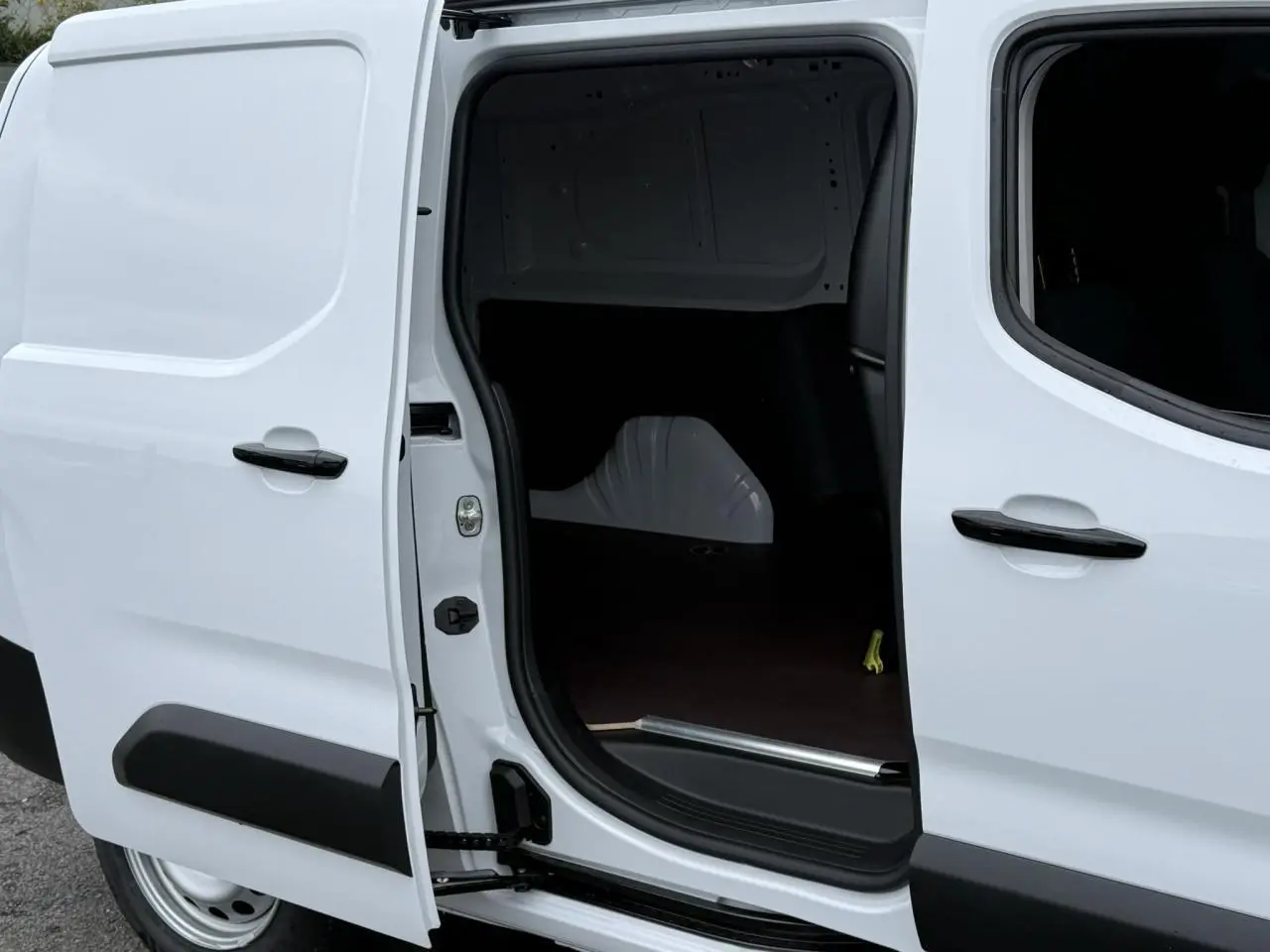 Vue latérale droite du Peugeot Partner blanc 2025 avec porte coulissante ouverte montrant l'espace de chargement vide.