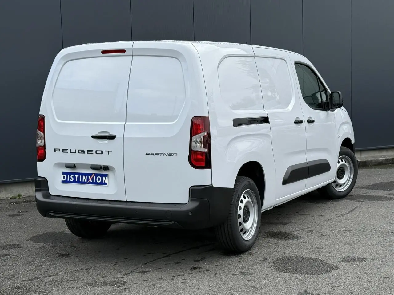 Vue 3/4 arrière droite d'un utilitaire Peugeot Partner blanc avec porte latérale coulissante et pare-chocs noirs.