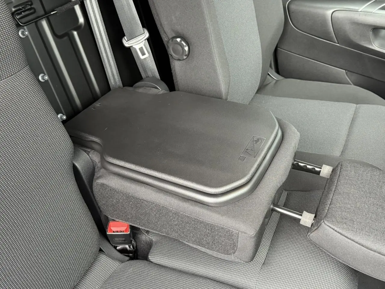 Détail intérieur montrant la banquette centrale rabattue avec tablette écritoire dans un Peugeot Partner XL blanc.