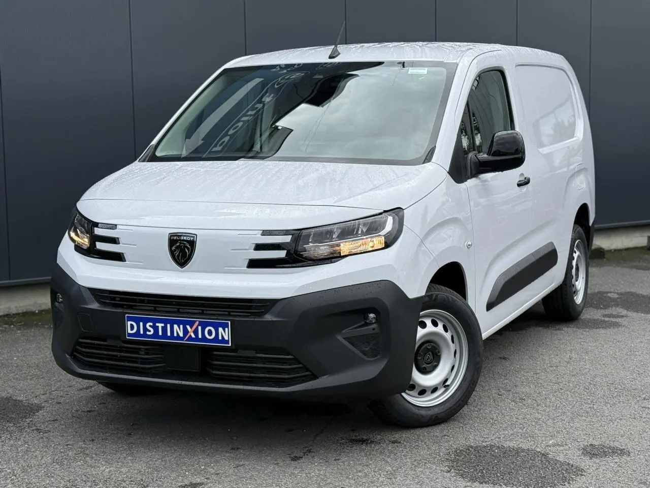 Vue 3/4 avant droite d'un utilitaire Peugeot Partner blanc avec pare-chocs noir et jantes acier.