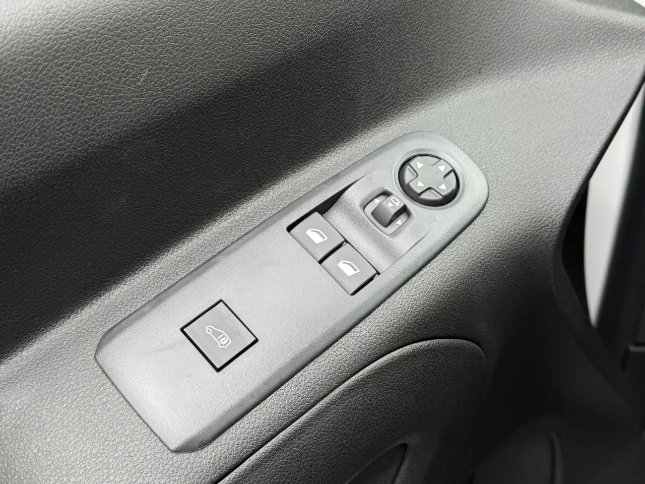 Gros plan sur les commandes de lève-vitres et réglage des rétroviseurs côté conducteur d'un Peugeot Partner blanc.