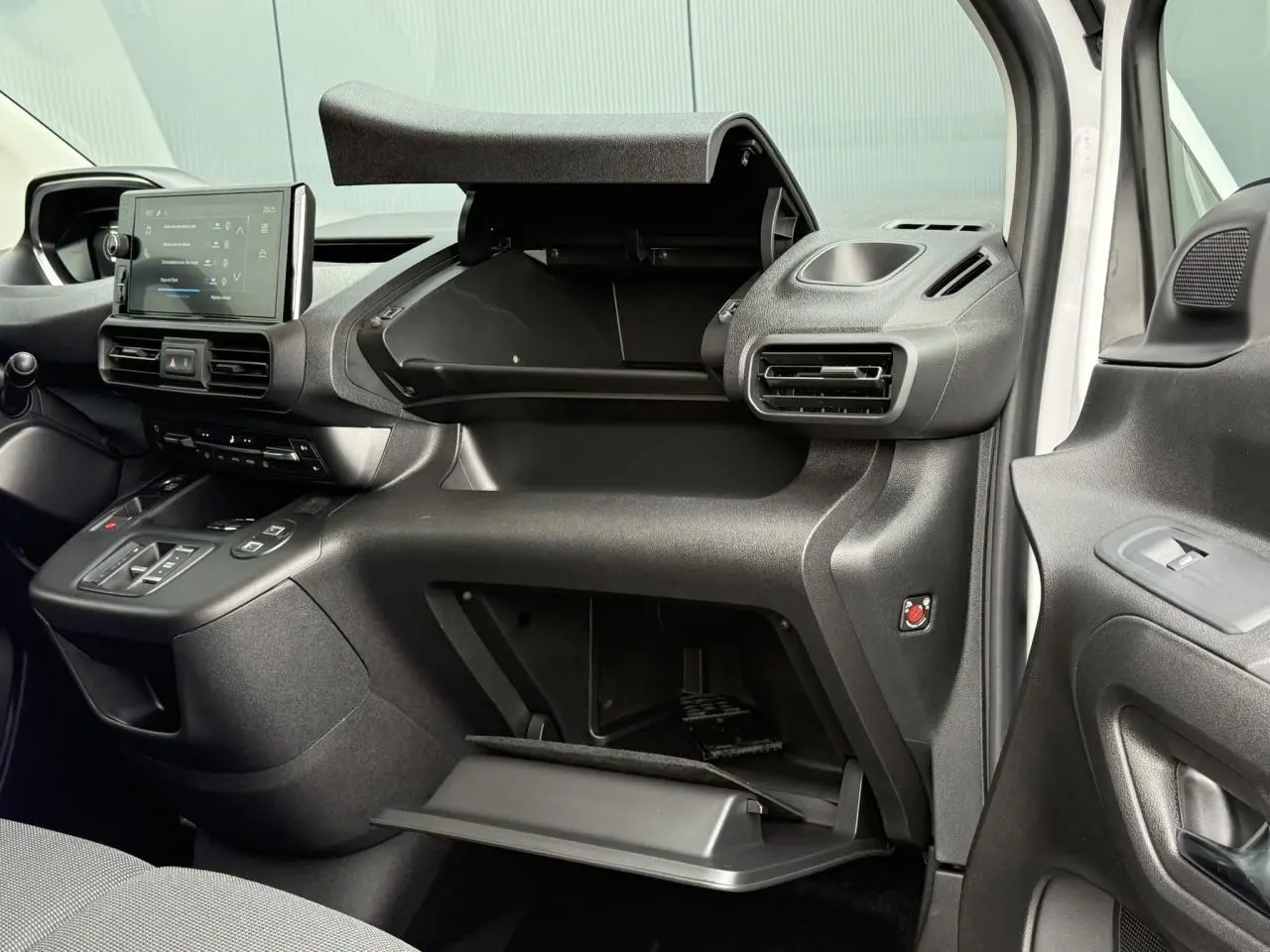 Intérieur côté passager du Peugeot Partner 2025 blanc, montrant tableau de bord et double boîte à gants ouvertes.