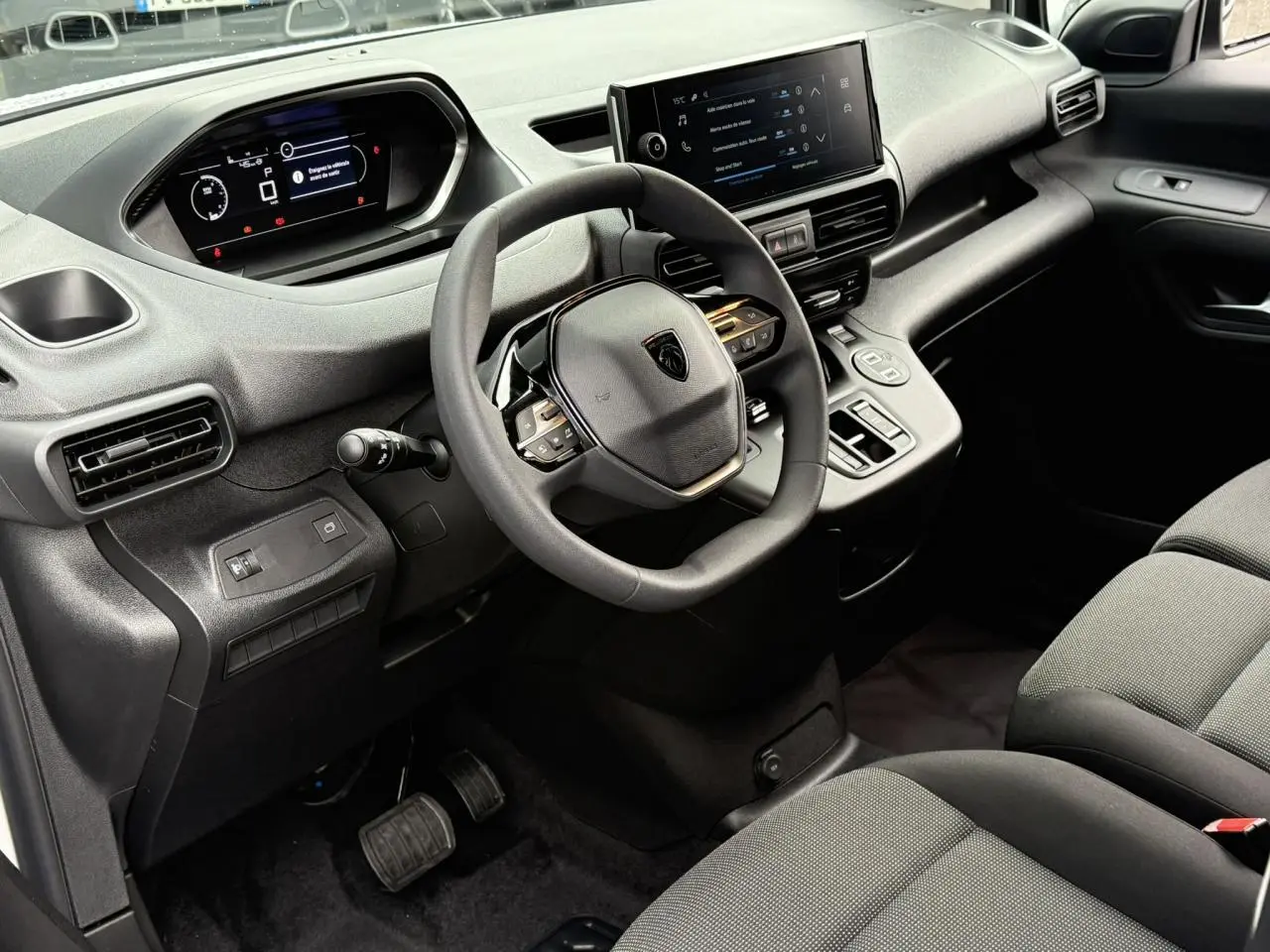 Vue intérieure côté conducteur du Peugeot Partner 2025 avec tableau de bord numérique et écran tactile central.