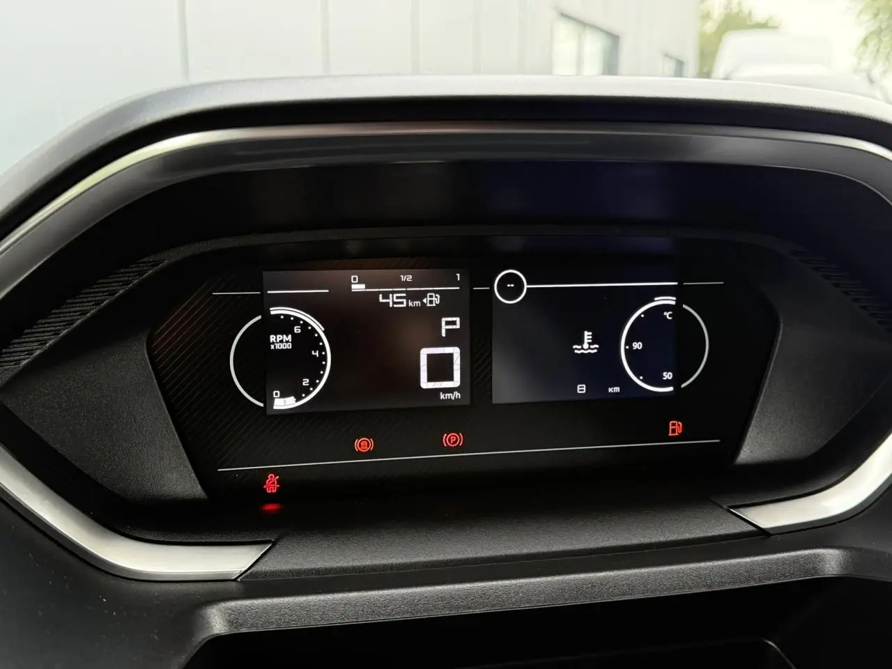 Tableau de bord numérique du Peugeot Partner 2025, affichant vitesse zéro et compte-tours, vue frontale rapprochée.